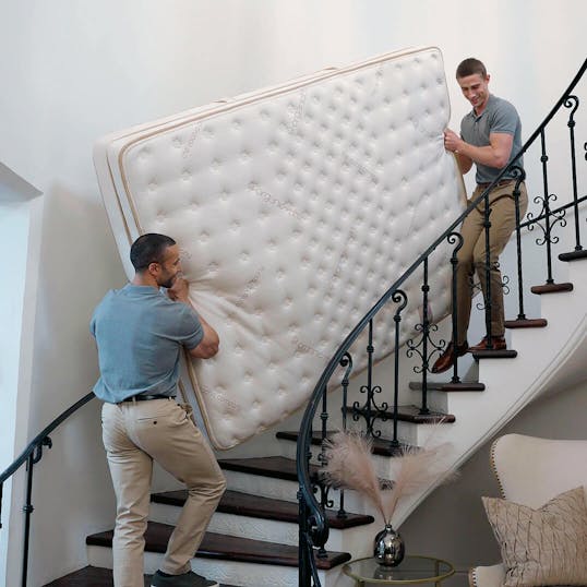 Two men carrying a Saatva mattress upstairs